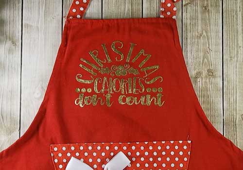 Make this cute heat embossed Apron for Christmas with this easy to follow tutorial. With a few tools and your Silhouette or Cricut machine, you'll be able to create this heat embossed Apron. This DIY project is easy and quick to make and is the perfect decoration for home. #ChristmasSilhouette #ChristmasCricut #ChristmasSVG