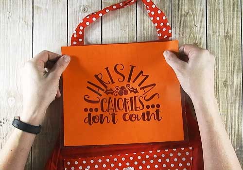 Make this cute heat embossed Apron for Christmas with this easy to follow tutorial. With a few tools and your Silhouette or Cricut machine, you'll be able to create this heat embossed Apron. This DIY project is easy and quick to make and is the perfect decoration for home. #ChristmasSilhouette #ChristmasCricut #ChristmasSVG