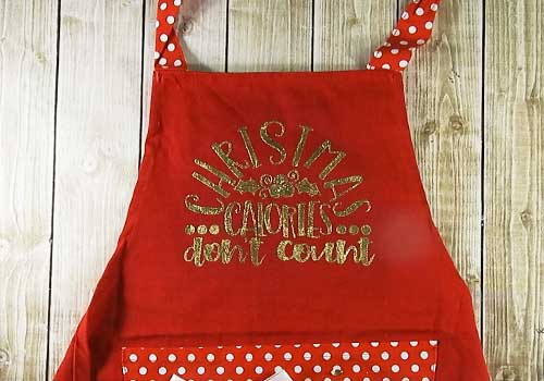 Make this cute heat embossed Apron for Christmas with this easy to follow tutorial. With a few tools and your Silhouette or Cricut machine, you'll be able to create this heat embossed Apron. This DIY project is easy and quick to make and is the perfect decoration for home. #ChristmasSilhouette #ChristmasCricut #ChristmasSVG