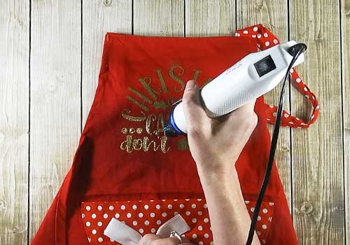 Make this cute heat embossed Apron for Christmas with this easy to follow tutorial. With a few tools and your Silhouette or Cricut machine, you'll be able to create this heat embossed Apron. This DIY project is easy and quick to make and is the perfect decoration for home. #ChristmasSilhouette #ChristmasCricut #ChristmasSVG