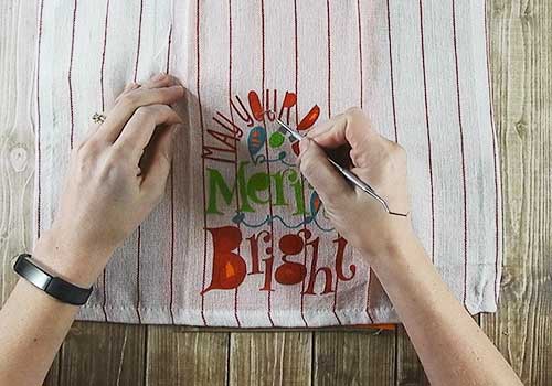 Make this cute Stenciled Dish Towel for Christmas with this easy to follow tutorial. With a few supplies and your Silhouette or Cricut machine, you'll be able to create this Stenciled Christmas Dish Towel for your home or as a gift. This DIY project is easy and quick to make and is the perfect decoration for home. #ChristmasSilhouette #ChristmasCricut #ChristmasSVG