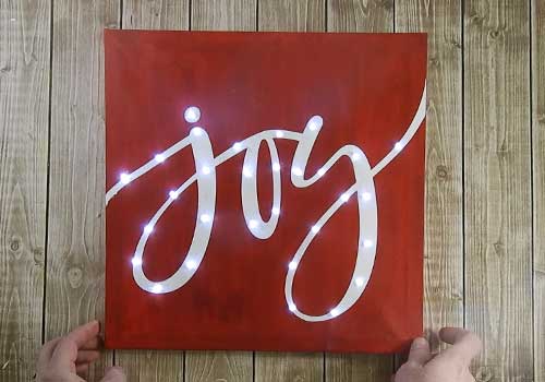 Make your own custom Lighted Christmas Canvas with your Silhouette or Cricut machine. This DIY project is easy and quick to make and is the perfect decoration for home. #ChristmasSilhouette #ChristmasCricut #ChristmasSVG #Christmascanvas